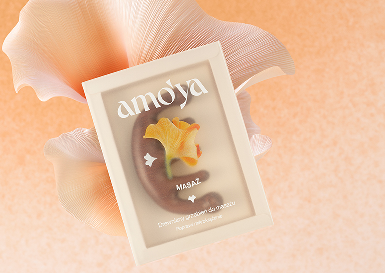 Baner AmoYa z drewnianym grzebieniem do masażu – produkt na tle płatków kwiatów.