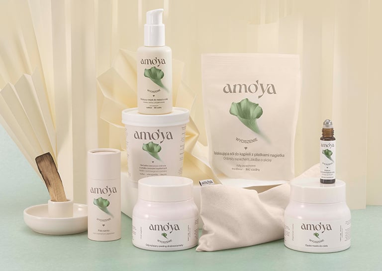 Produkty AmoYa Odpoczynek – balsam, krem do rąk, świeca i spray – na niebieskim tle z bąbelkami, promujące relaksującą pielęgnację.